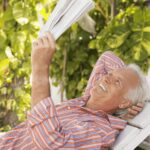 Elderly man reading newspaper without glasses