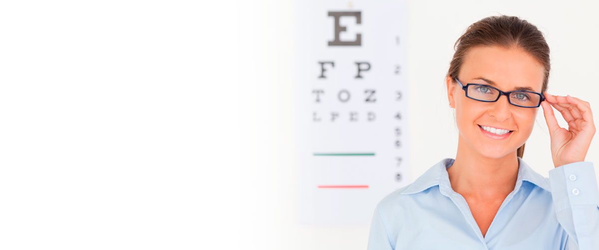 Smiling woman adjusting glasses with Snellen chart